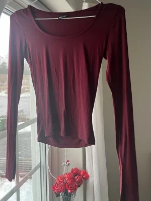 Vinröd långärmad topp Gina Tricot - Vinröd långärmad topp från Gina Tricot med rund halsringning. Tunn och stretchig modell i mjuk bomullsblandning, perfekt att styla med jeans eller kjol. Enkel och stilren design som funkar till många looks. Aldrig använd