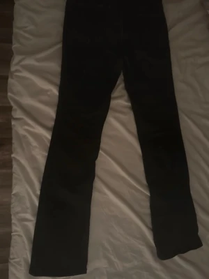 Svarta bootcut jeans - Säljer ett par svarta bootcut jeans med klassisk femficksdesign. Jeansen har raka ben med lätt utsvängning nedtill och är tillverkade i ett mjukt denimtyg. Perfekta för dig som gillar en tidlös och enkel stil.