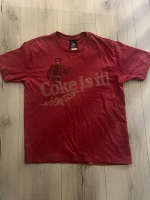 T-shirt ”Coke is it!”  - Säljer denna T-shirt med trycket ”Coke is it!” Från Junk food. 