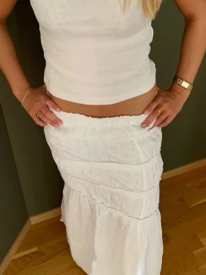 Vit långkjol med volangdetaljer - Supersöt vit långkjol med flera volangpartier och broderade detaljer. Säljer då den tyvärr är för kort för mig nu💞💞