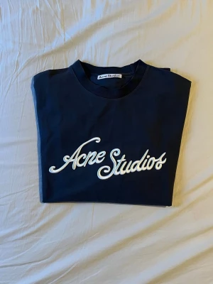 Grå Acne Studios Longsleeve - Snygg grå longsleeve från Acne Studios i storlek S med stor vit logga i skrivstil på bröstet och en mindre logga nere vid midjan. Endast använd ett fåtal gånger! Nypris: 4500kr, Mitt pris: 1499kr / Hör av er med minsta fundering 🌟🤗