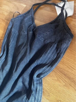 Mörkgrå body från Bershka - Cool grå body från Bershka med ribbad struktur och smala axelband. Bodyn har shortsdel och en figurnära passform som framhäver siluetten. Materialet är stretchigt och mjukt. Helt ny med prislapp