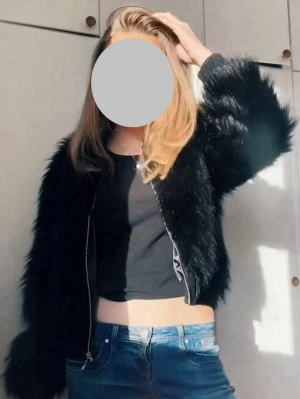 Svart fuskpälsjacka med dragkedja - Säljer en svart fuskpälsjacka med dragkedja framtill. Jackan har en kort, boxig passform och långa, fluffiga ärmar. Perfekt för dig som vill ha en trendig och varm look under vintern. Materialet är mjukt och ger en lyxig känsla. Jag har vanligtvis S/M💕