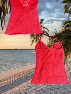 Röd ribbad linnetopp med smala band - Trendig röd linnetopp med smala axelband och ribbad struktur. Toppen har en lätt croppad passform och en liten volangkant nedtill. Perfekt för varma dagar och enkel att styla med jeans eller kjol.