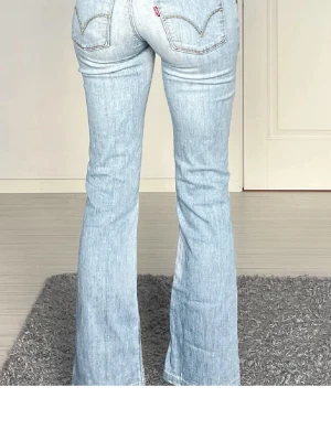 Ljusblå bootcut jeans från Levi's - Säljer ett par ljusblå bootcut jeans från Levi's med klassiska femficksdetaljer och snygga sömmar på bakfickorna. Jeansen har en utsvängd passform och är tillverkade i denim med en lätt tvättad look. Midjemått är ca 35, inerbenslängd ca 73. Två första är inte mina bilden!