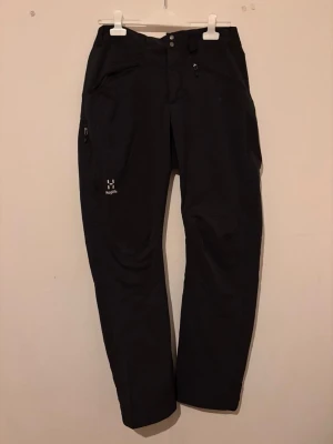  Haglöfs dri pant  - Snygga svarta  dri pant från Haglöfs med raka ben och flera praktiska fickor, inklusive dragkedjeficka på sidan. Tillverkade i slitstarkt funktionsmaterial som passar perfekt för aktiva dagar utomhus. Klassisk design med knapp- och dragkedjestängning.