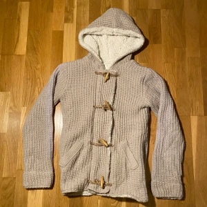 Unik fodrad cardigan - Mysig beige stickad jacka med huva och träknappar. Insidan är fodrad med mjuk fleece för extra värme (en av de skönaste plaggen jag har haft på mig). Perfekt för kyliga dagar. Ifall mer frågor eller bilder var inte rädda att skriva! Mvh