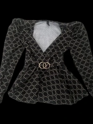 Svart mönstrad blus från Amisu!! - Supersnygg svart blus från Amisu med beige kedjeinspirerat mönster, markerade axlar och lång ärm. Djup v-ringning och bälte med guldfärgat spänne i midjan ger en riktigt trendig siluett. Perfekt för dig som gillar statement-plagg! Är i storlek XS är också lite större än på bilden💕