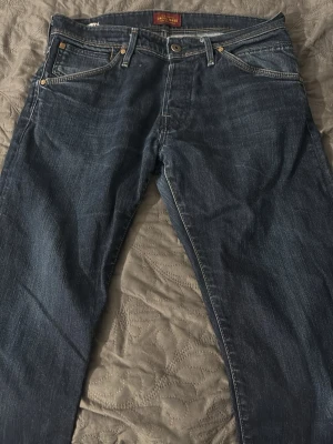 Blå jeans från Jack & Jones - Snygga blå jeans från Jack & Jones med klassisk femficksmodell och raka ben. Jeansen har kontrastsömmar och metallknappar. Tillverkade i slitstark denim som passar perfekt till en avslappnad stil.