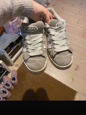 Grå Adidas Campus -  grå Adidas Campus sneakers, hål i båda hälarna inuti skorna.