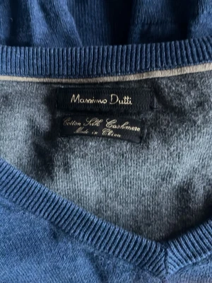 Blå tröja från Massimo Dutti - Mjuk blå tröja från Massimo Dutti i en mix av bomull, siden och kashmir. Tröjan har V-ringning och en enkel, klassisk design som passar till det mesta. Perfekt för dig som gillar stilrena och bekväma plagg.