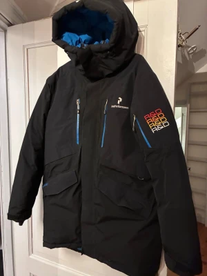 Svart dunjacka från Peak Performance - Säljer en Peak Performance Excursion P dunjacka i storlek L. Nypris ca 7 000 kr.  - Gore-Tex – vind- och vattentät - Löstagbar innejacka i polyester (kan användas separat) - Mycket varm – perfekt för vinter, skidsemester eller vardag - Flera praktiska fickor - Sparsamt använd, i fint skick  Färg: svart med blå insida. Rökfritt men katt finns i hemmet.   Kan skickas eller hämtas.