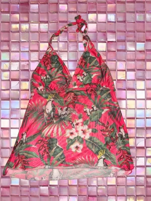 Rosa strandtopp  - Snygg strandtopp i rosa med tropiskt mönster. Halterneck-modell som knyts i nacken och lätt utsvängd passform. Materialet känns lätt och luftigt. använt få gånger