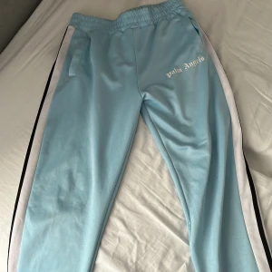 Palm Angels ljusblå mjukisbyxor säljer bara på vinted  - Palm Angels ljusblå mjukisbyxor med vita och svarta sidoränder. Byxorna har resår i midjan, fickor på sidorna och logga tryckt på vänster sida. Perfekta för en avslappnad och sportig look.