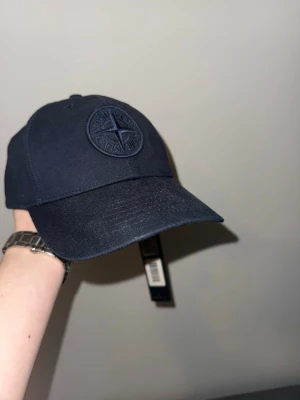 Mörkblå keps från Stone Island - Tjena! Säljer min Stone Island keps som är helt ny! Fick följde med när jag beställde min jacka men problemet är att jag inte passar i keps… Den är helt ny, lappar och allt finns fortfarande kvar! Kan tänka mig att sänka priset vid snabb affär för just nu ligger den bara och samlar damm… Mvh Oscar 