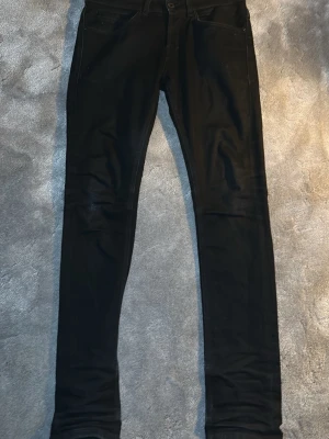 Svarta Dondup jeans - Säljer ett par svarta Dondup jeans med klassisk design och normal midja. Jeansen har smal passform hela vägen ner och är tillverkade i stretchigt material för extra komfort. Perfekta till en avslappnad streetstyle-look.