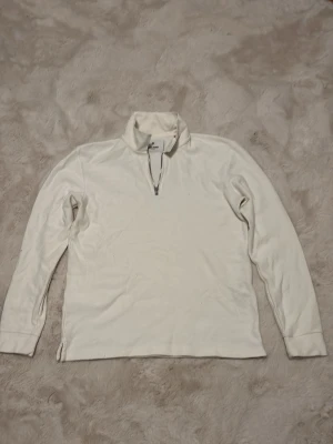 Vit half zip tröja från Jack & Jones - Snygg vit långärmad tröja från Jack & Jones Premium med half zip-dragkedja i halsen. Perfekt för lager på lager och enkel att matcha med olika outfits. Tröjan har en klassisk passform och mjukt material som känns skönt mot huden.