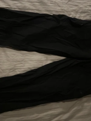 Svarta cargobyxor med fickor - Säljer ett par svarta cargobyxor med flera praktiska fickor på sidorna. Byxorna har en avslappnad passform och är perfekta för en streetwear-look. Materialet känns slitstarkt och de har klassiska cargodetaljer. Perfekt för dig som gillar funktionella och snygga byxor.