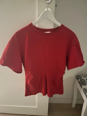 Röd croppad t-shirt - En enkel röd croppad t-shirt med rund hals och korta ärmar. T-shirten har en rak passform och är tillverkad i mjuk bomull, perfekt för en avslappnad och trendig look.