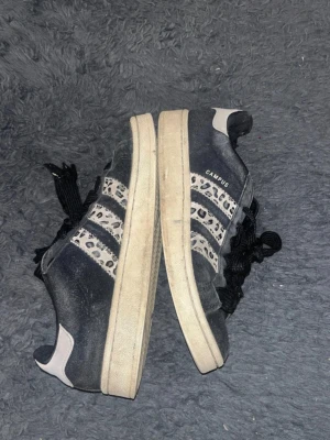 Adidas Campus sneakers leopardmönster - Säljer ett par svarta Adidas Campus sneakers med vita och leopardmönstrade detaljer på sidorna. Storlek 39