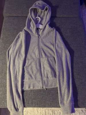 Grå zip hoodie från Gina Tricot - Snygg grå hoodie från Gina Tricot i storlek XS. Hoodien har dragkedja med ringdetalj, två fickor fram och en klassisk huva. Tillverkad i mjukt sweatshirtmaterial som är perfekt för chill dagar. Enkel och stilren design som passar till allt.