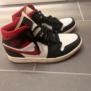 Nike Air Jordan 1 High svart/röd/vit - Nike Air Jordan 1 mid i klassisk svart, röd och vit färg. Skorna passar till båda tjejer och killar men är köpt i man storlek. Låda finns