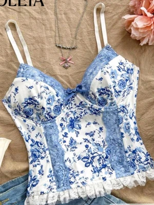 Blommig spetstopp med rosett - Supersöt topp med blått och vitt blommönster, spetsdetaljer i ljusblått och vit volangkant. V-ringad med liten blå rosett framtill och justerbara axelband. Perfekt för sommaren. Jag har aldrig använt den 