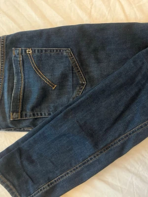 Mörkblå skinny jeans med kontrastsömmar - Snygga mörkblå jeans från Dondop. Jeansen är i modellen ”GEORGE” och är i storlek 32 men sitter som en 30/31. Jeansen är insydda därav har vi valt att gå ner 1 storlek från den ursprungliga. Skick 8/10 (en liten deffekt som inte syns vid användning. Tags finns.