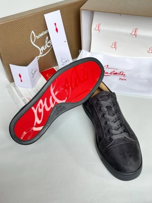 Svarta Louboutin sneakers med röd sula - Snygga svarta sneakers från Christian Louboutin med ikonisk röd sula. Skorna är låga och har ovandel i mocka och textil, svarta skosnören och diskreta sömmar. Perfekta för dig som vill ha en exklusiv och stilren look.