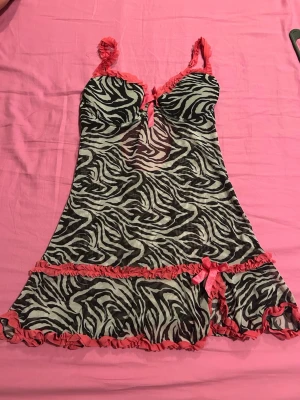 Rampage Sexig babydoll i zebra mönster - Superfin och feminin babydoll i svart/vitt zebramönster med söta rosa detaljer 🌸 Perfekt som nattlinne eller lingerie 💖 ✨ Lätt transparent tyg ✨ Inbyggd bh med bra stöd ✨ Justerbara axelband ✨ Söt rosett framtill ✨ Volang nertill som ger fin passform  Storlek: S / passar ca 75A–75B Märke: Rampage  Skick: väldigt bra skick då den knappt är använd  💌 Perfekt för mysiga kvällar eller när du vill känna dig extra fin!
