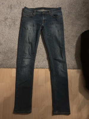 Nudie jeans Mörkblå lean dean  - Snygga mörkblå slim fit jeans från nudie i storlek w31/l34 med slitningar och klassisk femficksdesign. Jeansen har kontrastsömmar och en lätt tvättad look som ger en cool vibe. Passar perfekt till en avslappnad stil och är tillverkade i denim med stretch. Priset är diskuterbart. Topp skick. Hör av er vid frågor 👍