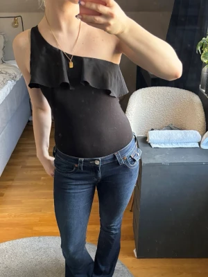Topp  - Säljer en svart oneshoulder topp med snygg volangdetalj över bröstet!🖤 Priset är diskuterbart vid snabb affär🥰 