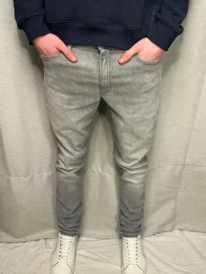 Ljusgråa dondups - Säljer ett par ljusgrå dondup iris jeans med klassisk femficksdesign och dragkedjegylf. Jeansen har en modern, smal passform och är tillverkade i mjuk denim med lite stretch. Passar runt 32/32-31/32