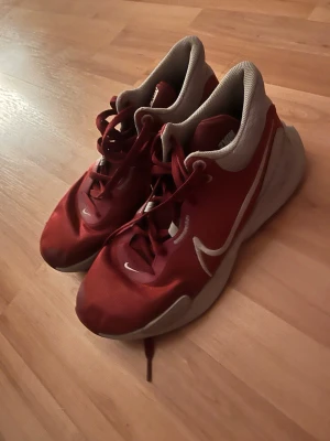Nike elevation basketskor  - Snygga röda Nike sneakers med vit sula och vita detaljer. Skorna har en låg profil och är tillverkade i mesh och syntetmaterial för bra andningsförmåga. Klassisk Nike-logga på sidan och skön innersula. Perfekta för dig som gillar sportig stil.