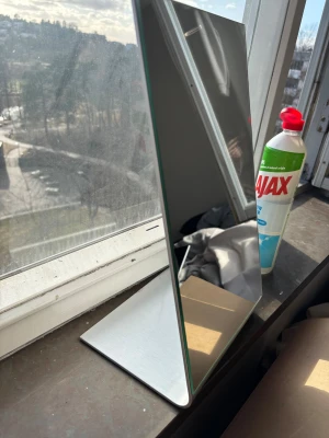 Hämtas enbart upp i Sundbyberg (fraktar ej) - Stilren sminkspegel med rektangulär form och minimalistisk design. Spegeln har en stadig fot i borstat metall och själva spegelglaset är tunt och elegant. Perfekt att ha på sminkbordet eller i badrummet för att fixa sminket.