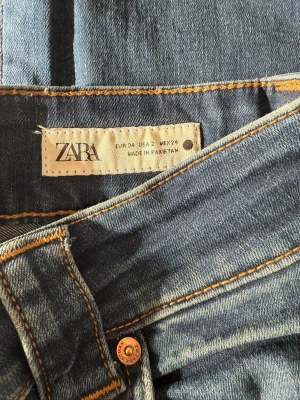 Blå raka jeans från Zara - Säljer ett par blå bootcut jeans från Zara med snygga kontrastsömmar. Perfekta för en avslappnad och trendig look.