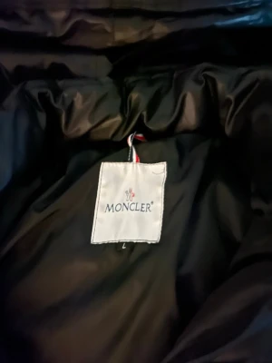 Moncler maya - Säljer en svart dunjacka från Moncler i storlek L. Jackan har klassisk Moncler-logga på insidan och är certifierad enligt DIST för spårbar dunfyllning. Perfekt för kalla vinterdagar och har en stilren look. Jätte andvänd men endå bra. Passar som M