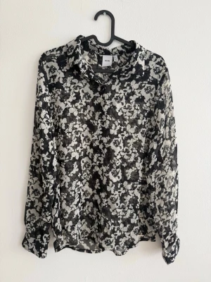 ICHI Blommig Skjorta - Svart/Vit - Strl 36 - Snygg och stilren skjorta från Ichi i svart med vitt blommönster. Lätt och luftig modell som passar både till vardag och lite mer uppklätt.  Skjortan är knappt använd och i mycket fint skick. Klassisk krage och knäppning framtill.  Storlek: 36 Märke: Ichi Färg: Svart/vit blommig Material: 100% Polyester  Perfekt till jeans, kostymbyxor eller kjol 🌸