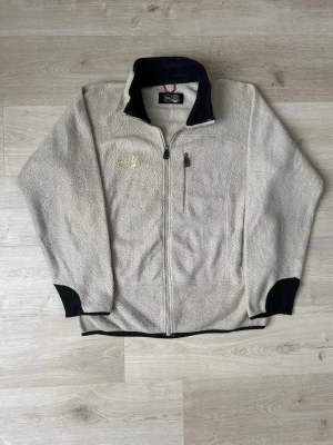 Beige FILA fleecejacka Storlek L - Fin Fila fleece i beige färg. Jackan är i mycket bra skick och sparsamt använd. |  Äkta som allt annat jag säljer! ✅ |  Storlek: L | Skick: Mycket Bra Skick - Tyvärr ett hål vid ena ärmen och ena draget på en dragkedja (SE SISTA BILD) | Färg: beige | Märke: Fila | Modell: Fleecejacka |  Hör gärna av dig vid frågor så svarar jag så fort jag kan! 😁|   (SKU - 88)