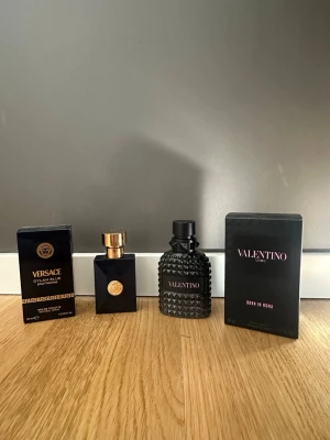 Versace och Valentino parfymduo, Luleå - Två exklusiva parfymer: Versace Dylan Blue Pour Femme i mörkblå glasflaska med gulddetaljer och Valentino Uomo Born In Roma i svart, noppad glasflaska med svart lock. Båda med tillhörande eleganta förpackningar. 