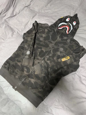 BAPE camo shark hoodie - Tja! Säljer en mörkgrå/svart camo extremt sällsynt BAPE hoodie, modellen innan den som säljs idag som främst såldes i Asien. Storlek XXXL men sitter som en XL. Säljes då den tyvärr inte kommer till användning alls längre, hör av dig vid funderingar/prisförslag! ✌️