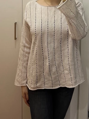 Ljusbeige stickad tröja med hålmönster - Säljer en ljusbeige stickad tröja med raka ärmar och diskreta lodräta hålmönster. Tröjan har en rund halsringning och är tillverkad i ett mjukt, tunt material som ger en avslappnad look.