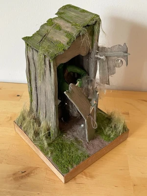 Miniatyr utedass med träsktroll  - Unik handgjord miniatyr av ett gammalt utedass i trä med detaljer som trasig dörr, konstgjord mossa och gräs. Monterad på en träram och dekorerad med naturtrogna effekter som sliten look. Perfekt som dekoration eller samlarobjekt.