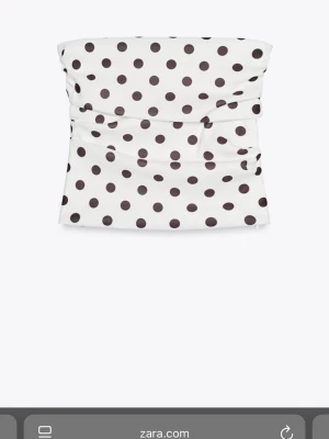 Vit prickig bandeau tubtopp från Zara - Snygg bandeau tubtopp från Zara i vit färg med svarta prickar. Toppen är axelbandslös och har en lätt rynkad design som ger en cool och modern look. Perfekt att matcha med jeans eller kjol för en trendig outfit.