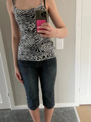 Mörkblå denim shorts med fickor - Säljer ett par mörkblå denim shorts med klassiska fickor fram och bak. Shortsens längd går ner till knäna och de har kontrastsömmar som ger en cool look. Passformen är normal och materialet är robust bomull. Perfekt för dig som gillar en avslappnad och stilren stil.