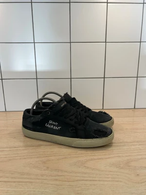 Saint Laurent - Svarta saint Laurent sneakers. Med slitningar. Storlek 42 men sitter lite mindre. skick 7/10 Inga defekter. Men en lite sliten sula som ni ser på bilden. Nypris 5000kr. 