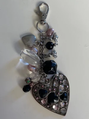Y2K keychain/bag charm - Keychain/bag charm med berlocker och pärlor, gjord av mig. Det stora hjärtat har missfärgningar på metallen (se sista bild) , men jag tycker att det bidrar till en mer unik look💕