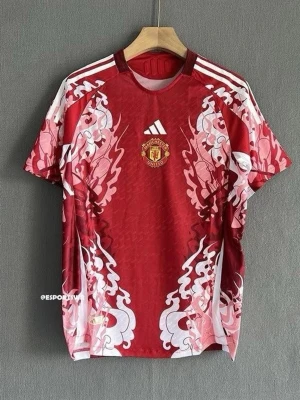 Manchester United röd matchtröja Adidas - Snygg röd Manchester United matchtröja från Adidas med vita och rosa grafiska mönster längs sidorna och axlarna. Tröjan har klassiska vita Adidas-ränder på axlarna och klubbmärket på bröstet. Perfekt för fotboll eller träning.