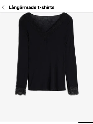 Svart Intimissimi tröja  - Svart långärmad topp från Intimissimi med v-ringning och spetsdetaljer vid halsringning och ärmslut. Använd ett par få gånger, som ny