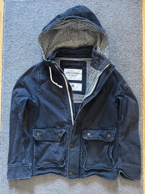 Vintage Abercrombie&fitch Field/parkajacka - Säljer denna as feta Abercrombie & Fitch Fieldjackan med luva, med rutigt mönster inuti |Mycket bra skick, lite urtvättad| Storlek M | Längd ≈ 67cm, Bredd armhåla - armhåla ≈ 55cm | Modell 175, 68kg | 